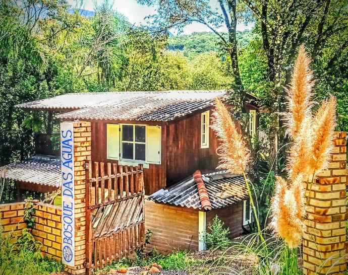 Fachada da Casa do Bosque com deck e cercada pela mata atlântica